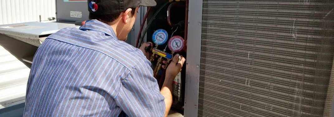 HVAC technician servicing a condenser unit in Van Buren