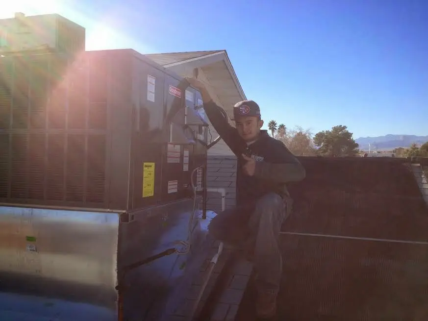 HVAC technician performing Air Duct Cleaning on a rooftop unit in Van Buren